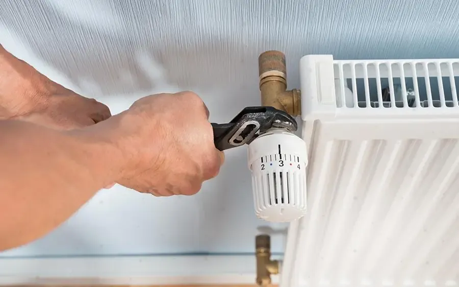 Réglage d'un robinet thermostatique de radiateur par un chauffagiste dans les Yvelines